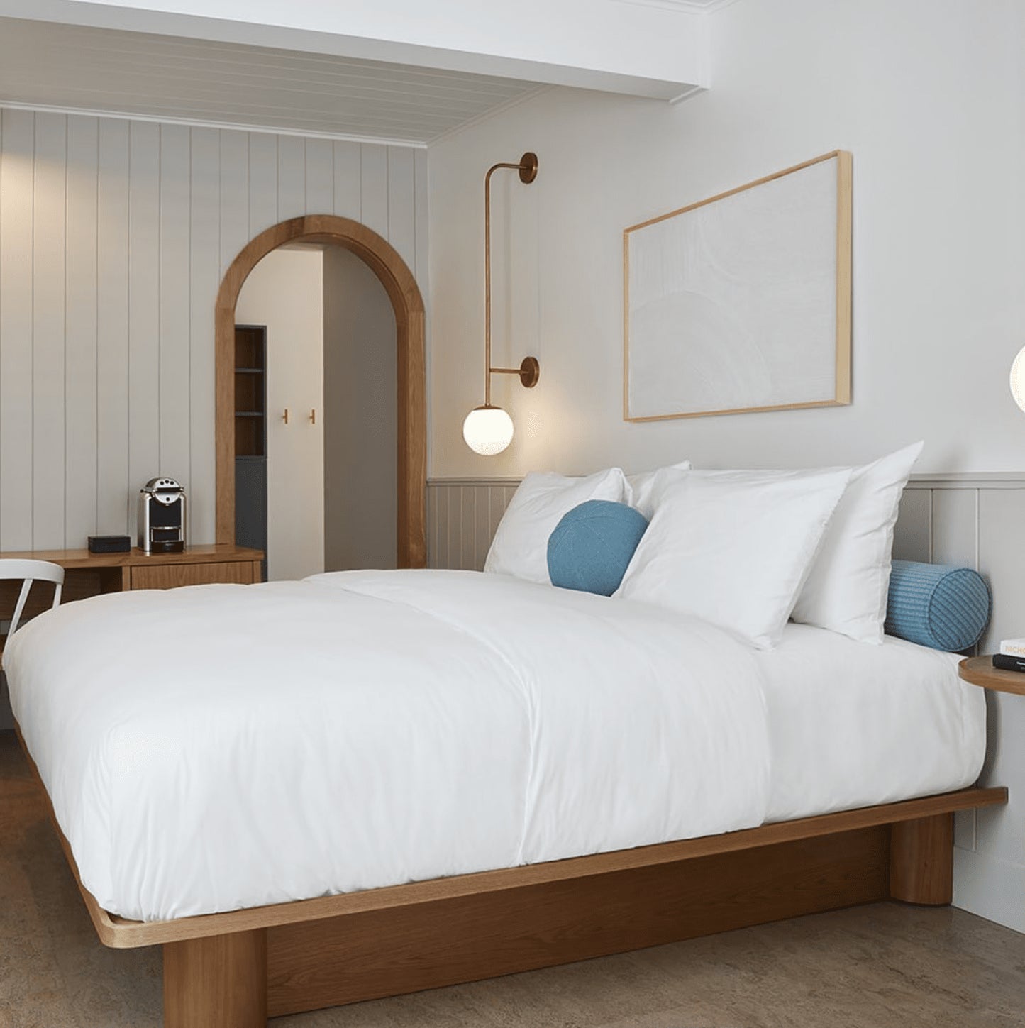 a bedroom with white bedding and tongue and groove panelling on the wall and ceiling