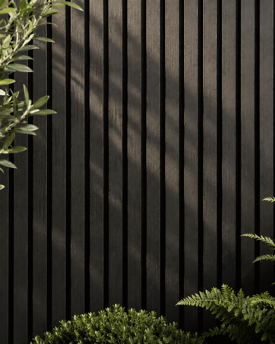 Black slatted wall with green plants in the foreground