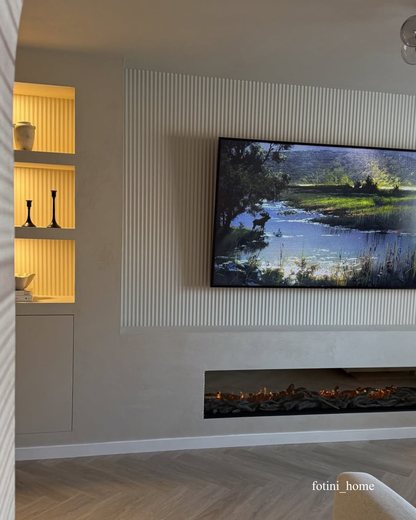 Modern living room with a television displaying a nature scene, a fireplace, fluted wall panelling and a shelf.
