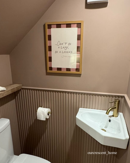 Bathroom with a half wall panelling, a sink, toilet, and framed quote on the wall.