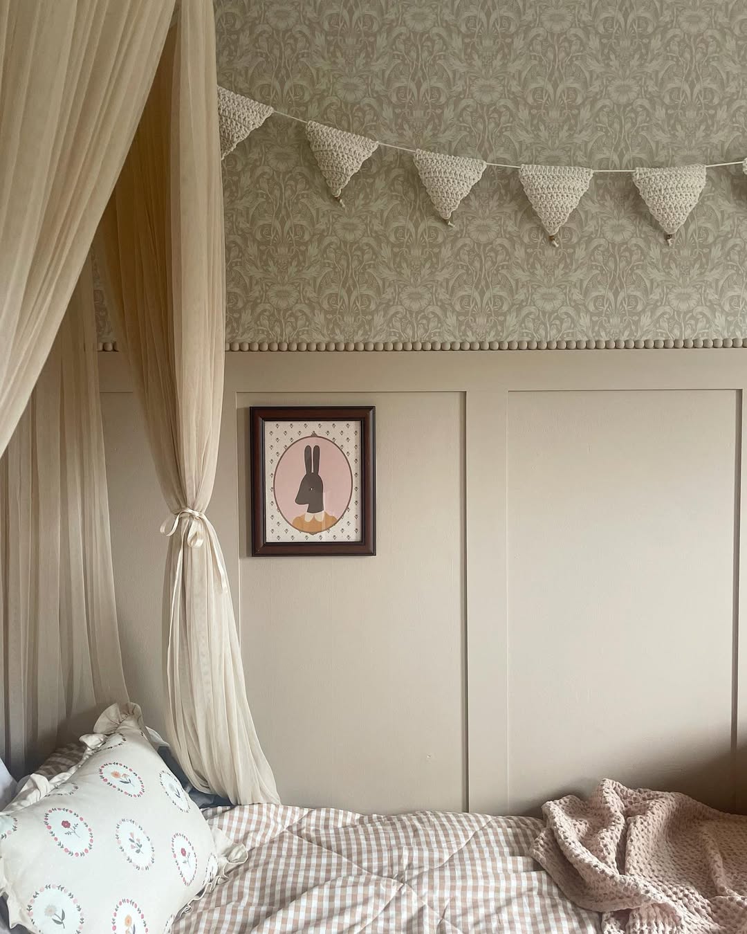 Bedroom with canopy, patterned wallpaper, and framed picture on shaker panelled wall.