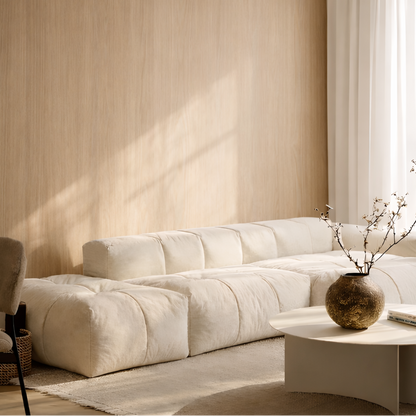 Beige sectional sofa in a oak panelled living room with a small table and decorative vase.