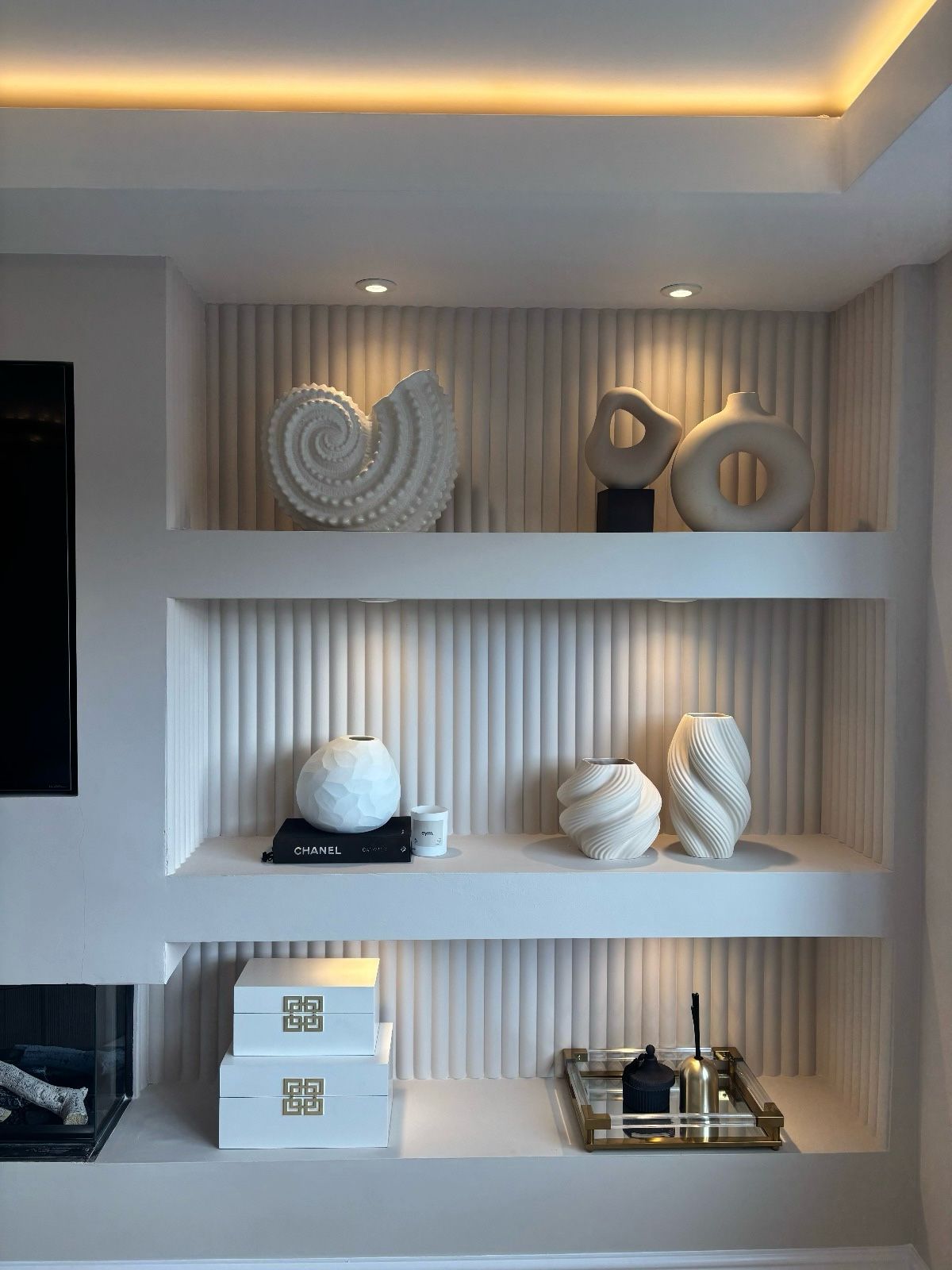 ribbed wall panelling as a backdrop on living room tv wall shelving. Netural decor and ornaments.