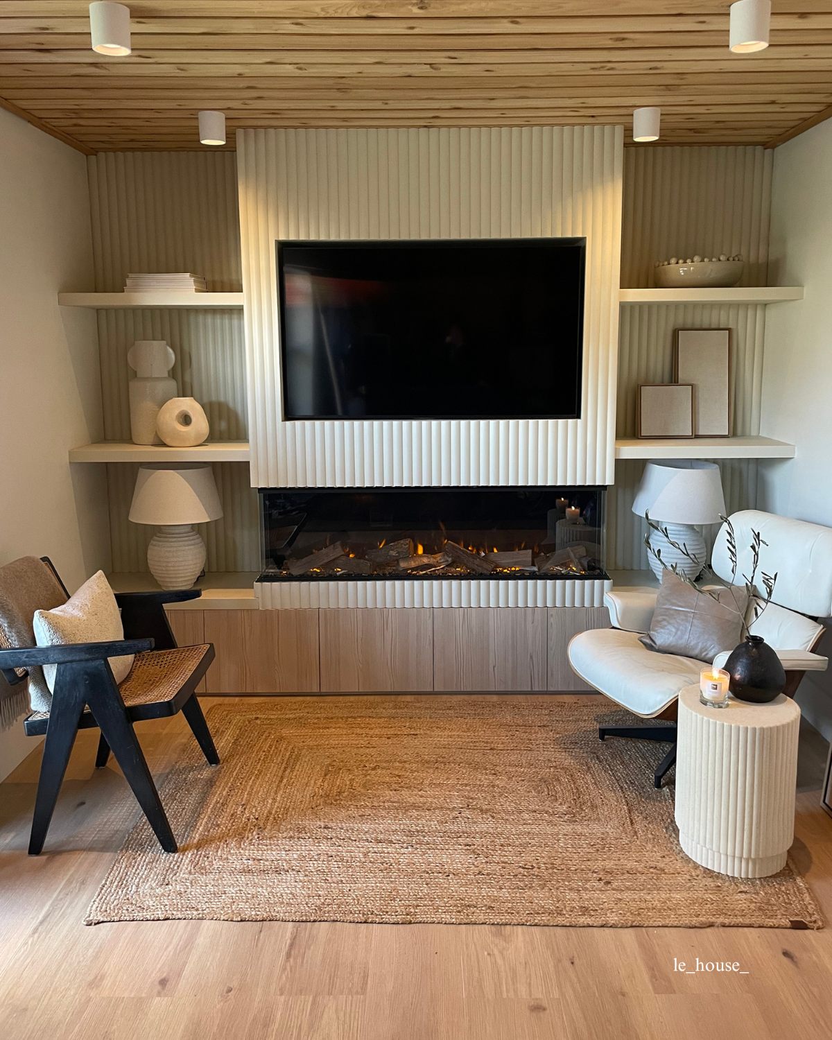 a cosy living space with a wooden ceiling and tv wall featuring white ribbed wall panels.