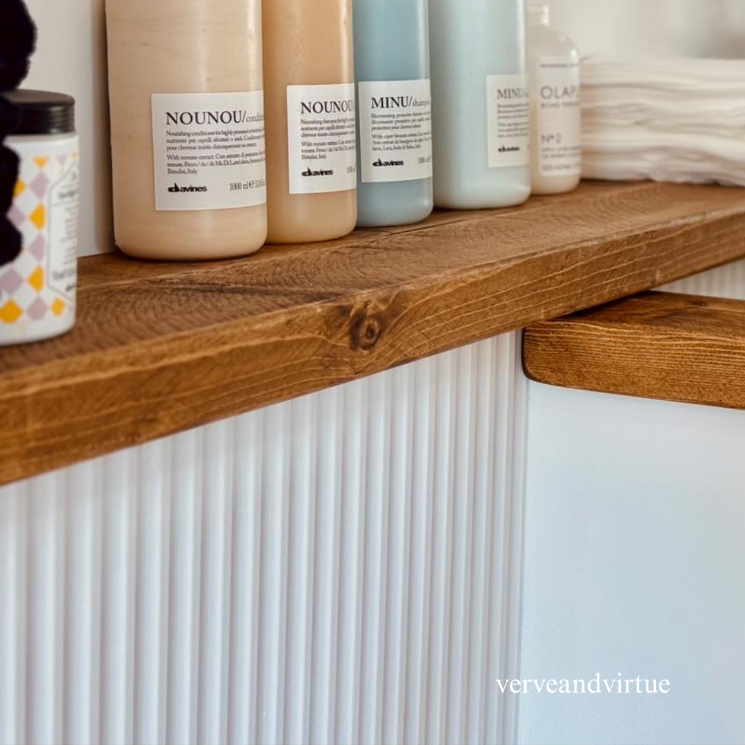 Wall panelling below a wooden salon shelf with various bottles 
