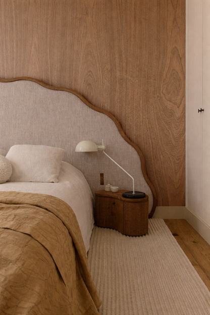 Bedroom with wood panelling and nightstand, featuring a lamp and decorative items.
