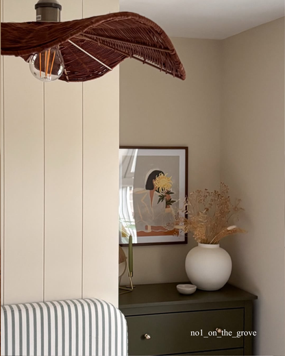 Decorative leaf-shaped light fixture above a bed and tongue and groove wall panelling