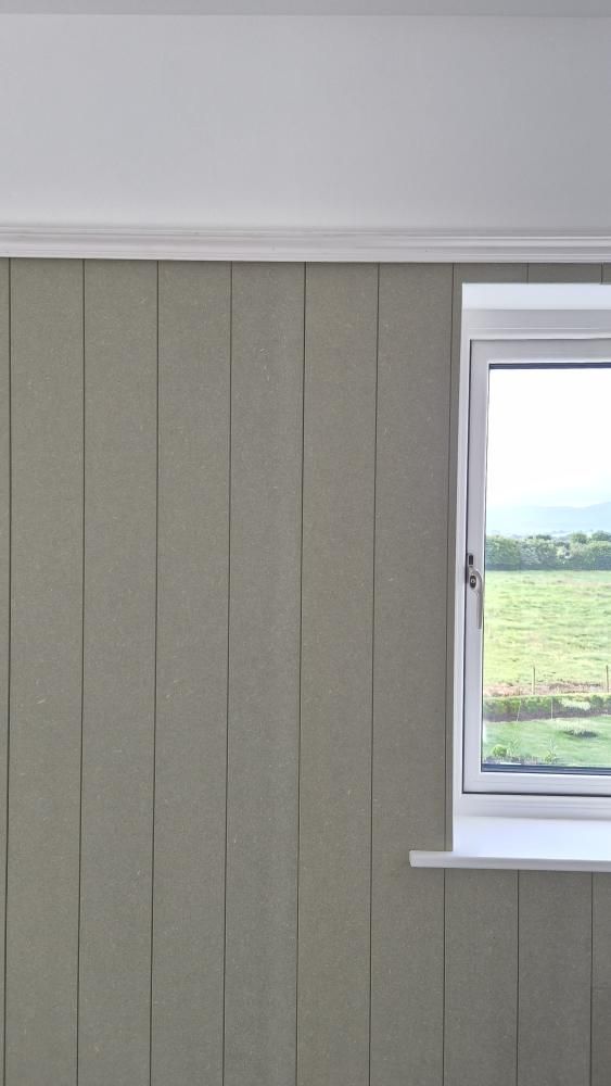 Window with white frame on a gray tongue and groove paneled wall