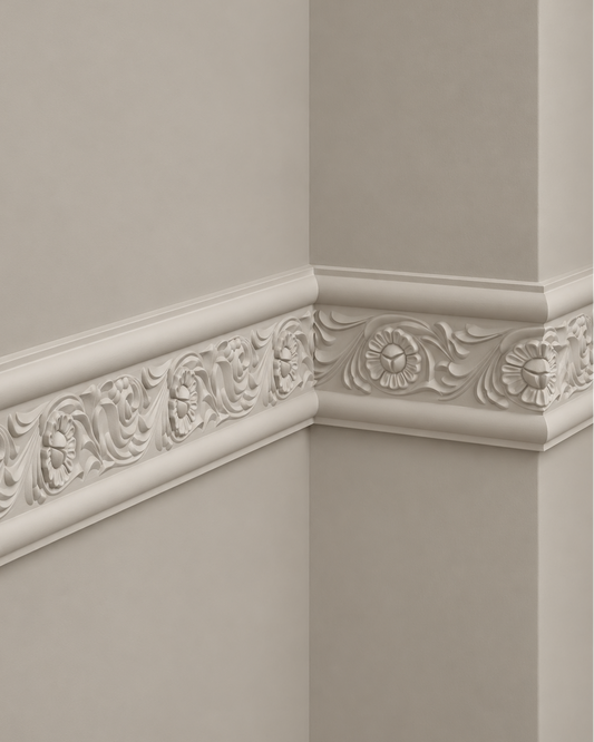 Decorative white plaster cornicing molding with intricate floral and scrollwork relief, installed along the corner of a beige wall.