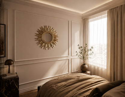Neatly decorated bedroom with a sunburst mirror on the wall with panelling.