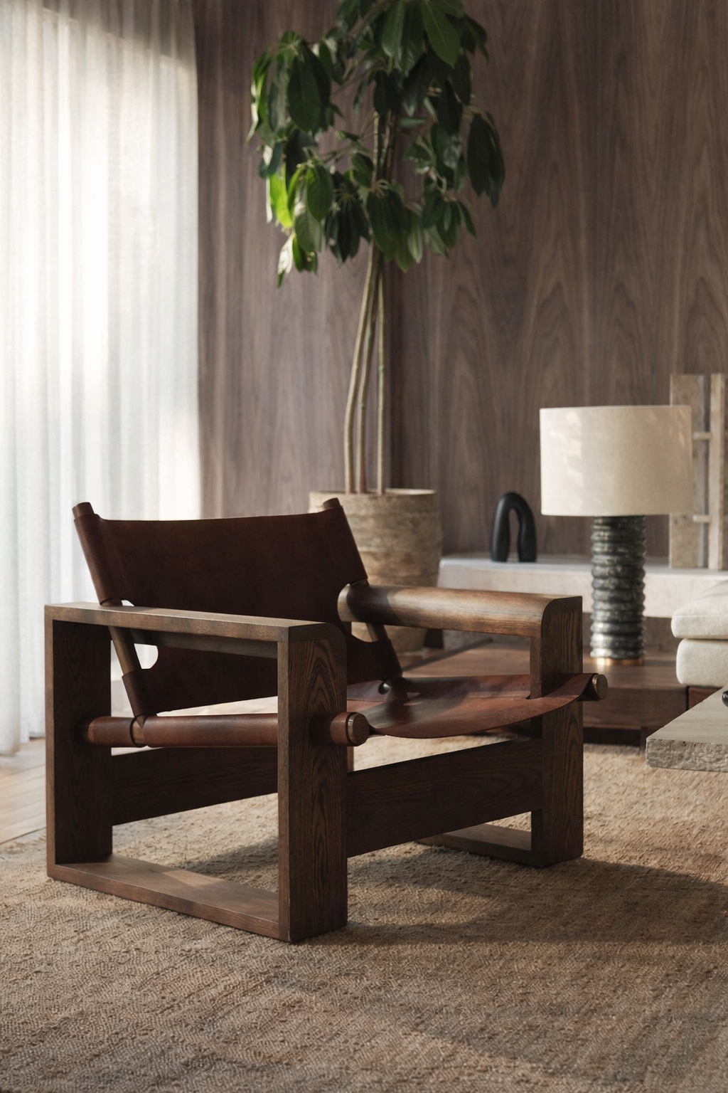 Wooden chair in a room with a plant, lamp and walnut wall backdrop