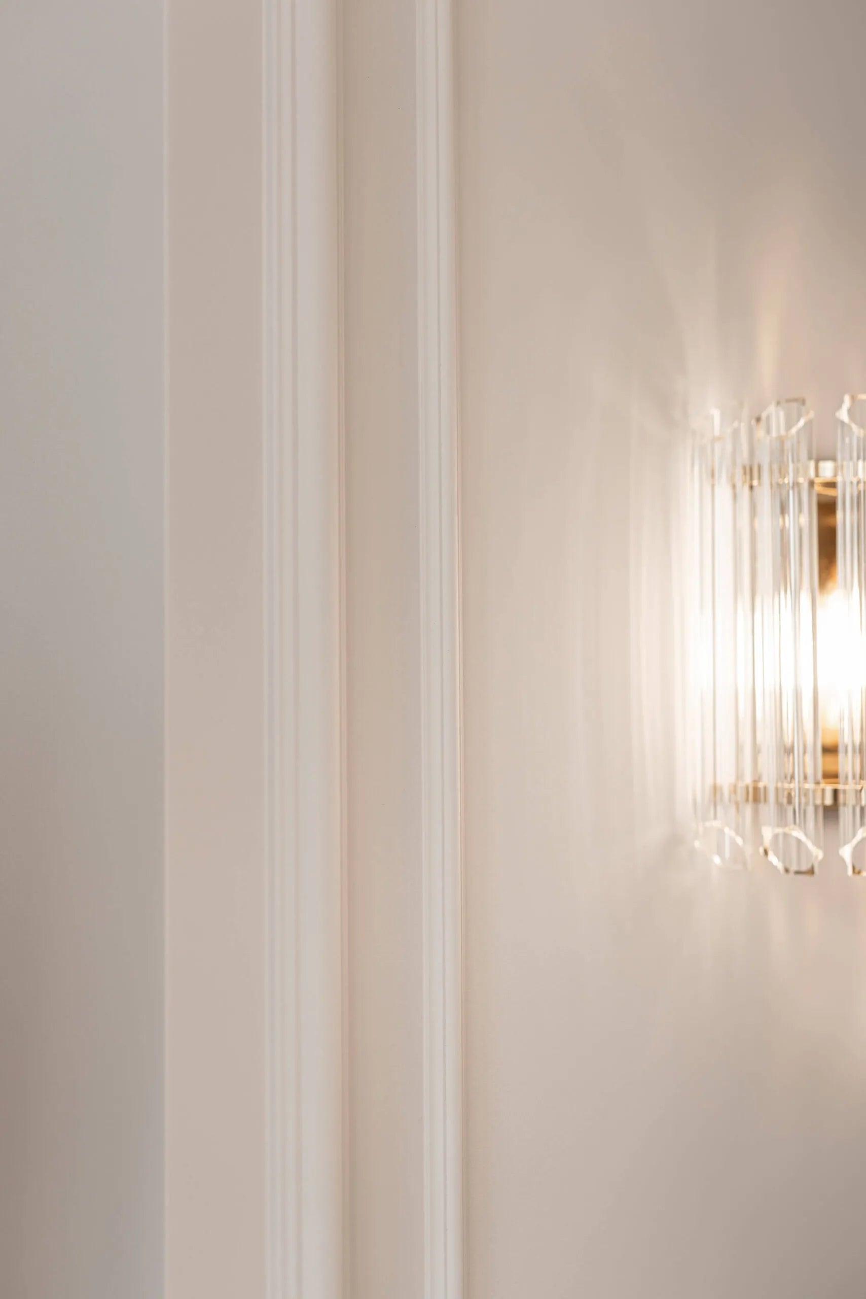 Decorative wall light fixture on a neutral wall with vertical wall panelling