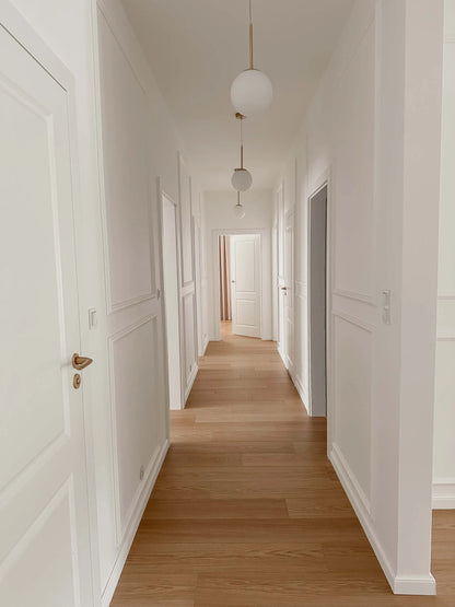 Long hallway with white wall panelling and wooden floor